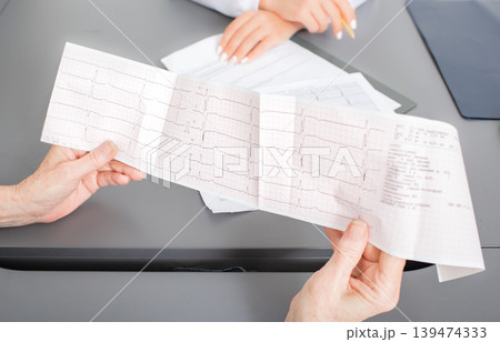 Senior patient looking at the results of a cardiogram of heart in a cardiologist's office. Diagnostics and treatment of arrhythmias, coronary heart disease, and heart failure 139474333