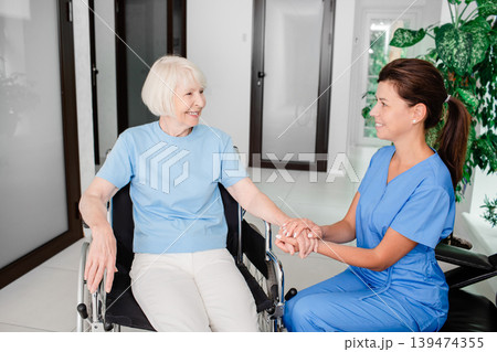 Smiling nurse and elderly woman patient in a wheelchair. Medical care for people with disabilities 139474355