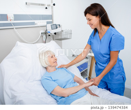 Friendly nurse taking care of a senior woman in a hospital room. Treatment of elderly patients Friendly nurse taking care of a senior woman in a hospital room. Treatment of elderly patients 139474384