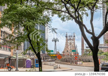 New york, usa august 17,2024. Queensboro bridge connecting manhattan and queens, with the roosevelt island tram tower and city street framed by trees in new york city 139474390