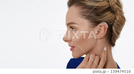 Portrait of woman with hearing aid behind the ear for treatment deafness, side view. Hearing aids, hearing solutions 139474510