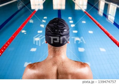 Swimmer wearing a swimming cap, standing near pool, get ready start swimming, back view. Swimmer wearing a swimming cap, standing near pool, get ready start swimming, back view. 139474757