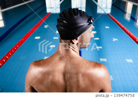 Swimmer wearing a swimming cap, standing near pool, get ready start swimming, back view. Swimmer wearing a swimming cap, standing near pool, get ready start swimming, back view. 139474758