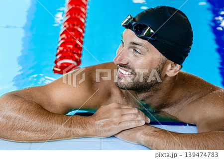 Smiling swimmer looking away, relaxing on the rooftop pool. Swimmer in the swimming pool,headshot Smiling swimmer looking away, relaxing on the rooftop pool. Swimmer in the swimming pool,headshot 139474783