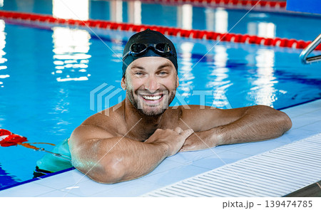 Positive swimmer, wearing swim goggles and swimming cap, relaxing in the pool after training. Positive swimmer, wearing swim goggles and swimming cap, relaxing in the pool after training. 139474785