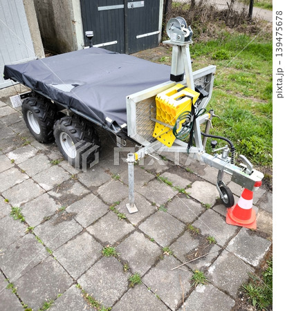 A two-axle ATV trailer with a black tarpaulin in a parking lot A two-axle ATV trailer with a black tarpaulin in a parking lot 139475678