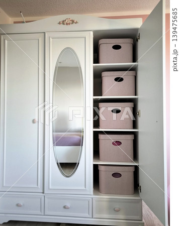 A classic white wardrobe with an open door and pink boxes. A classic white wardrobe with an open door and pink boxes. 139475685