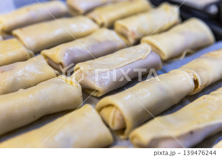 Top View of Many Uncooked Crepe Rolls with Meat Filling on a Tray Top View of Many Uncooked Crepe Rolls with Meat Filling on a Tray 139476244