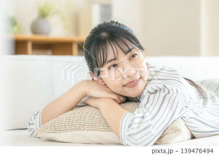 リビングで寝転んでくつろぐ眼鏡の若い女性 リビングで寝転んでくつろぐ眼鏡の若い女性 139476494