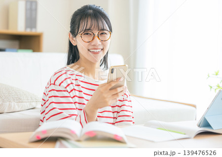 スマホを見ながら勉強する若い女性 139476526