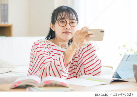 スマホを見ながら勉強する若い女性 139476527