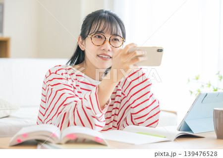 スマホを見ながら勉強する若い女性 139476528