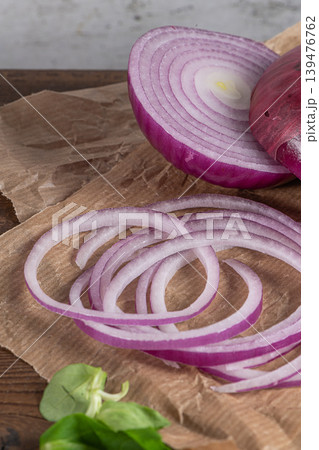 Wooden cutting board on old wooden table top with tablecloth, sliced red onion and cucumber and corn salad 139476762