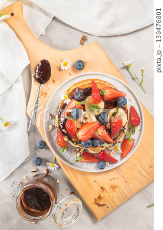 Pancakes with chocolate paste and hazelnuts, banana, strawberry and blueberry Pancakes with chocolate paste and hazelnuts, banana, strawberry and blueberry 139476801