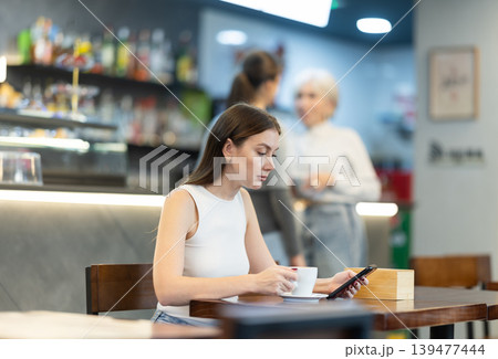 Young woman sitting in cafe and chatting on mobile phone 139477444