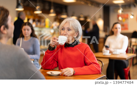 Senior woman in cafe sits opposite male companion, has nice conversation 139477484
