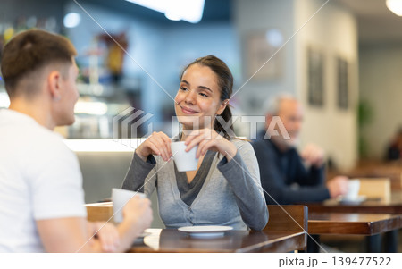 Girl in cafe sits near guy companion, has nice conversation Girl in cafe sits near guy companion, has nice conversation 139477522