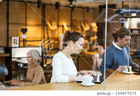 Interested female designer sitting in cafe with coffee and laptop 139477573