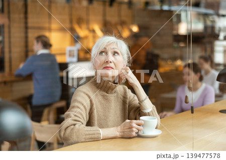 Calm mature woman enjoying peace and quiet alone in cozy cafe 139477578