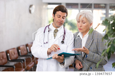 Adult male doctor and elderly woman with documents folder 139477657
