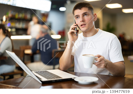 Guy working on laptop and answering call Guy working on laptop and answering call 139477659