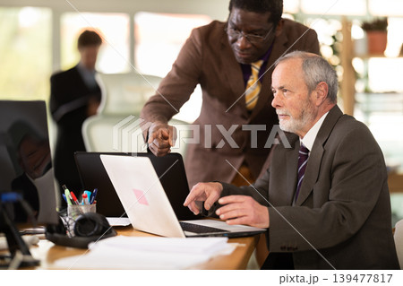 African businessman helps an employee with a program on a laptop 139477817