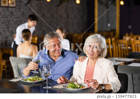 Happy senior couple having dinner together in restaurant Happy senior couple having dinner together in restaurant 139477823