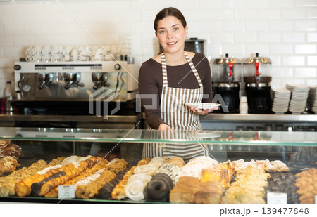Bakery saleswoman offers to buy delicious pastry 139477848
