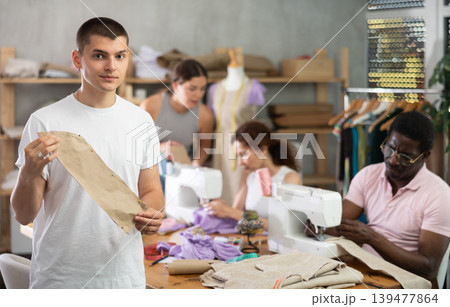 Young guy showing paper pattern in training sewing workshop 139477864