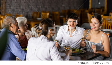 Young couple enjoying dinner with senior parents in restaurant Young couple enjoying dinner with senior parents in restaurant 139477929
