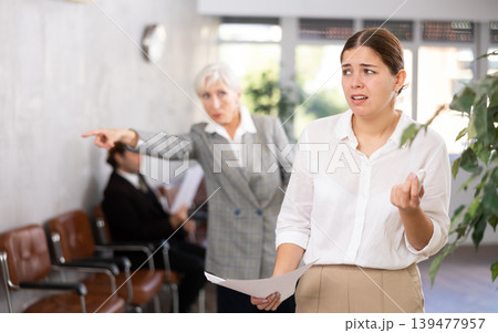 Crying young female office worker scolded by angry woman boss Crying young female office worker scolded by angry woman boss 139477957