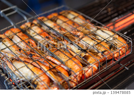 Fresh grilled river prawns cooking on metal barbecue rack with glowing heat seafood street food dinner closeup with smoky atmosphere and appetizing texture Fresh grilled river prawns cooking on metal barbecue rack with glowing heat seafood street food dinner closeup with smoky atmosphere and appetizing texture 139478085