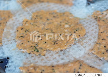 Closeup of Vietnamese rice paper crackers with sesame and herbs pressed on patterned sheets prepared for drying and traditional cooking process Closeup of Vietnamese rice paper crackers with sesame and herbs pressed on patterned sheets prepared for drying and traditional cooking process 139478090