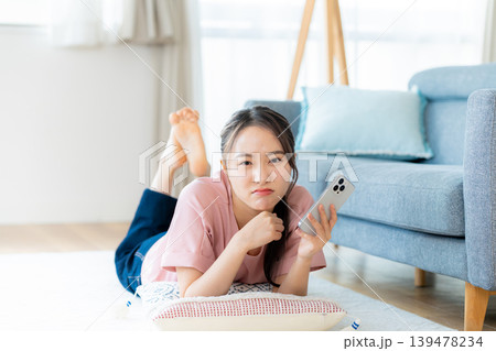 部屋でスマホを操作する若い女性 139478234