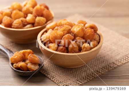 Dried longan in a wooden bowl with spoon on a wooden background 139479169