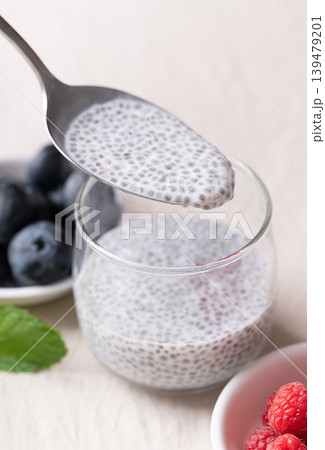 Eating chia pudding with fresh raspberries and blueberries in a glass, Healthy food Eating chia pudding with fresh raspberries and blueberries in a glass, Healthy food 139479201