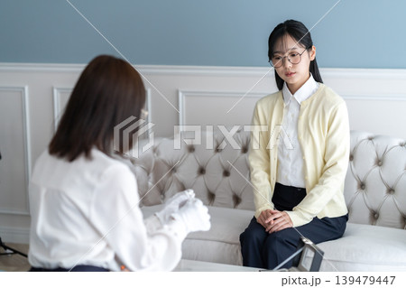 出張買取で自宅を訪問した鑑定士の説明を真剣に聞く女性客 139479447