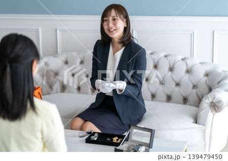 タイトル候補 笑顔で丁寧に時計の査定結果を説明する女性鑑定士 タイトル候補 笑顔で丁寧に時計の査定結果を説明する女性鑑定士 139479450