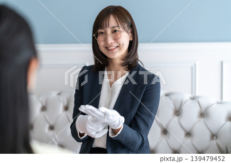 タイトル候補 笑顔で丁寧に時計の査定結果を説明する女性鑑定士 タイトル候補 笑顔で丁寧に時計の査定結果を説明する女性鑑定士 139479452
