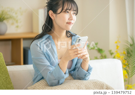リビングでスマホを見る若い女性 139479752