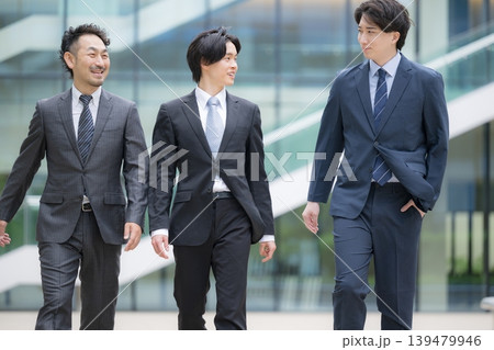 都会のビル背景で笑顔で横並びで歩くハンサムな営業チーム、法人営業や企業成長など若手から管理職 都会のビル背景で笑顔で横並びで歩くハンサムな営業チーム、法人営業や企業成長など若手から管理職 139479946