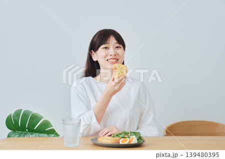朝食を食べる笑顔の若い女性 139480395