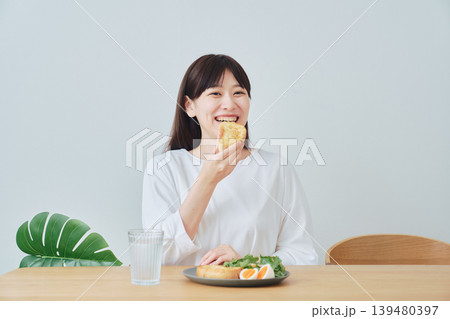 朝食を楽しむ笑顔の若い女性 朝食を楽しむ笑顔の若い女性 139480397