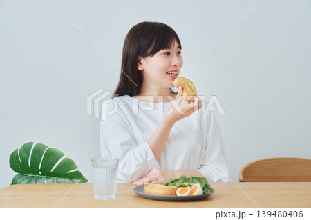 朝食のパンを食べる若い女性 朝食のパンを食べる若い女性 139480406