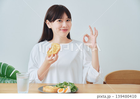 朝食を食べてOKサインをする若い女性 朝食を食べてOKサインをする若い女性 139480410