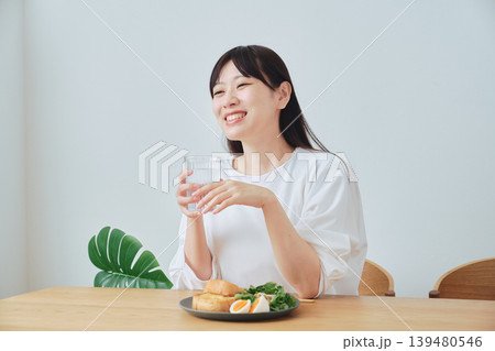 朝食をとりながら話を聞く女性 朝食をとりながら話を聞く女性 139480546