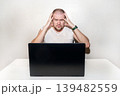 Stressed man grabs head in anger and frustration while working on a laptop, feeling overwhelmed 139482559
