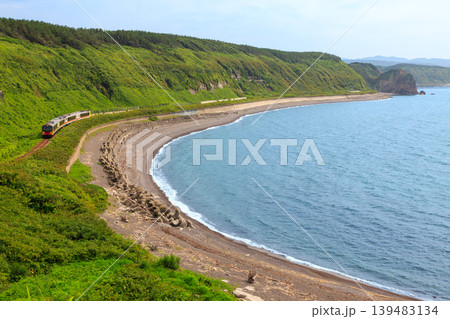 日本海に沿ってアーチ形の海岸を走る五能線のリゾート列車を塩見崎から遠望する 139483134