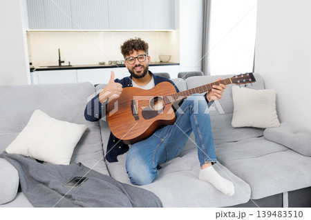Happy musician playing acoustic guitar giving thumbs up Happy musician playing acoustic guitar giving thumbs up 139483510