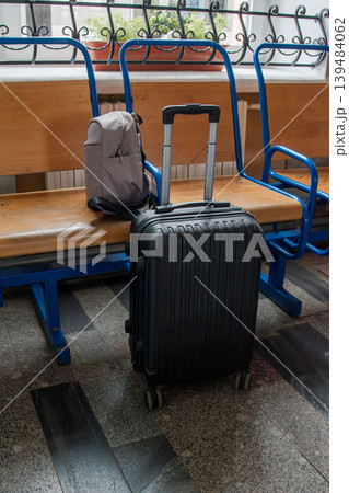 Black suitcase on wheels at railway station waiting area Black suitcase on wheels at railway station waiting area 139484062